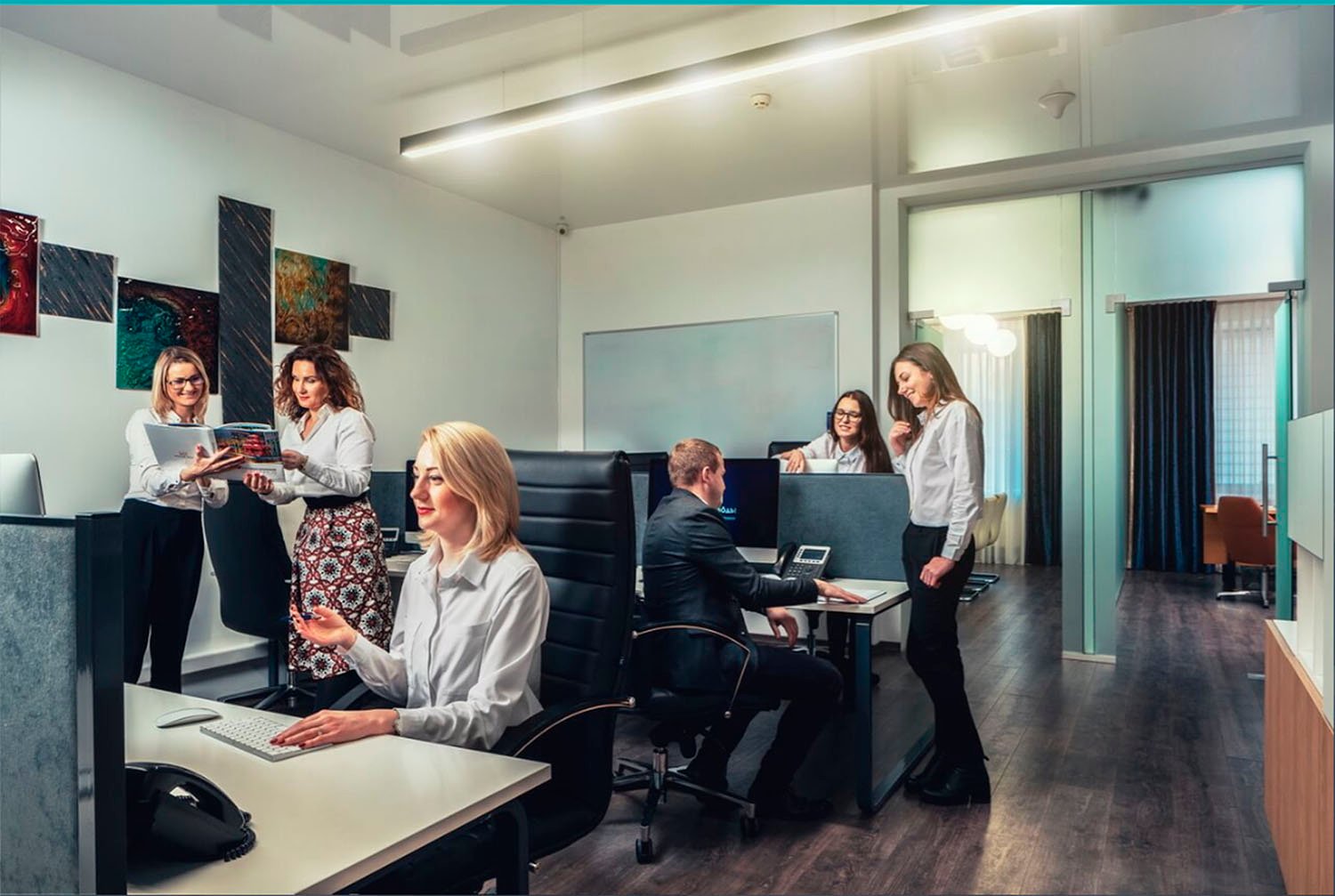 Сотрудники SKYFORM STUDIO работают в открытом офисном пространстве, групповые обсуждения за рабочими столами, современный интерьер с произведениями искусства на стенах.